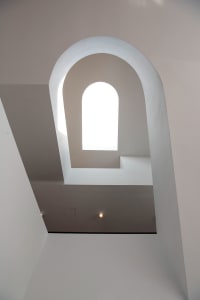 White arch-shaped stairwell with a bright window at the center.