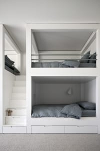 A modern minimalist bedroom with white walls and wooden bunk beds