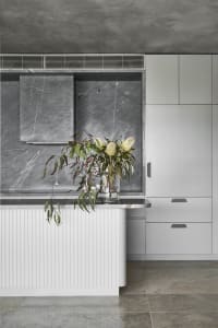 A minimalist kitchen featuring natural stone counter tops and a marble backsplash.