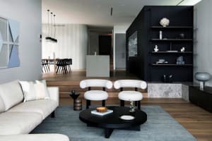 Modern living room featuring a concrete and black metal design with white furniture and a circular coffee table.