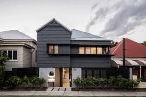 Modern house with dark metal cladding and white accents, featuring a metal roof and white-painted trim.