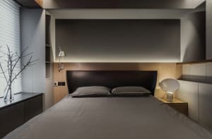 A minimalist bedroom featuring concrete texture walls, a LED-lit headboard, and modern furniture.