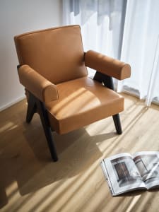 A modern leather armchair with dark wooden legs and a cushioned seat and backrest.