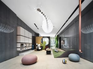 A modern living room featuring composite materials, including a pink and a blue pouf, a green upholstered chair, and minimali