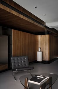 A modern office interior featuring wood paneling and a minimalist black chair.