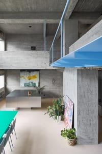 A modern, minimalist interior with concrete walls and a metal kitchen island.