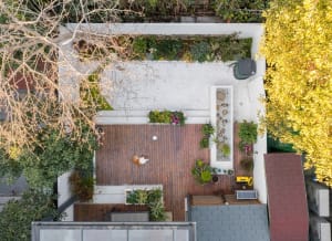 Aerial view of a modern minimalist garden featuring a wooden deck, concrete patio, and assorted plants.
