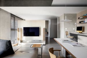 A modern, minimally styled living room with concrete tiles, a sleek sofa, and minimal furnishings.