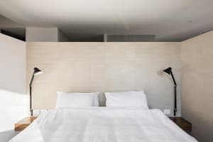 A minimalist white bedroom with modern design elements.