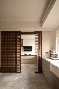 Modern kitchen with wooden lattice divider and marble countertops.