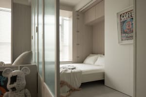 A minimalist bedroom with a wooden bed, white bedding, and textured fabric pillows.