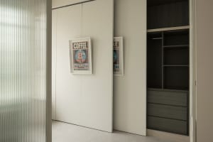 Minimalist modern closet with white sliding doors and black minimalist design, featuring framed posters.