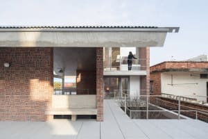 A modern industrial residential exterior with red brick and concrete materials.