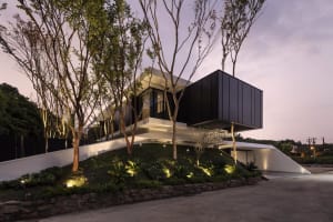 A modern residential building with concrete and glass features at dusk.