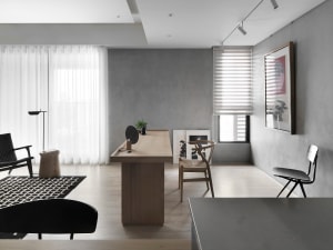 A modern home office with concrete walls, a wooden desk, and a glass window.