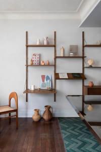 Minimalist floating shelves displaying various ceramic objects and books in a simple, modern interior design setting.