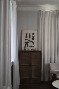 Minimalist living room featuring neutral textiles and a wooden cabinet.