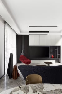 A modern living room featuring a textured black couch, a sleek black chair, and a marble floor. Modern design elements includ