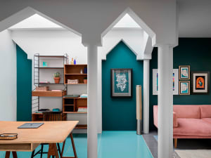 A modern living room with teal walls, a pink sofa, and white columns.