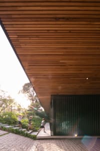 A modern building with a wooden exterior features a sloped roof and a garden area.