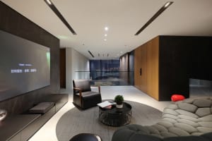 Modern living room with marble and wooden accents, featuring a circular coffee table and a large flat-screen TV.