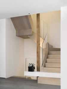 Modern minimalist staircase with wooden steps and glass railings.