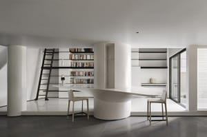 A modern library with a concrete floor and minimalist design, featuring a curved desk and bookshelves.