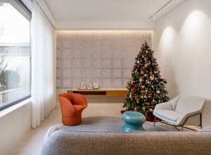 A minimalist living room decorated for the holidays with a Christmas tree adorned with lights and ornaments, along with a sue
