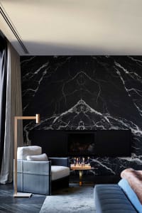 A modern living room with a marble wall and a fireplace.