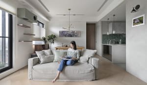 A modern living room with a concrete floor, wood furniture, and a fabric sofa.