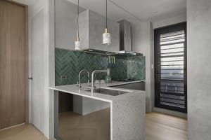Modern kitchen featuring terrazzo countertops and green herringbone backsplash tiles.