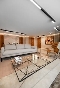 Modern minimalist living room with a glass coffee table and beige sofa, showcasing sleek design and contemporary style.