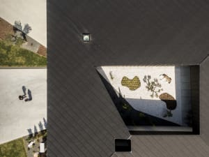 Top-down view of a modern rooftop garden featuring concrete and gravel surfaces with plants.