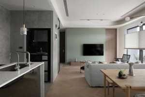 A modern living room featuring concrete walls, wooden flooring, and fabric couches.