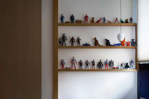 A wooden shelf with various toy figurines and dinosaur models arranged neatly on white walls.