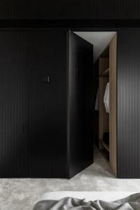 Modern interior view of a black closet with wood elements showing minimalist design