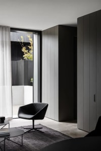 A modern living room featuring sleek black furniture, concrete flooring, and a large window with natural light.