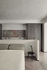 A modern bedroom features concrete walls and wooden furniture.