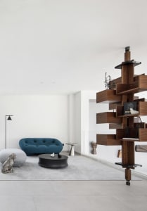 Modern living room with concrete floor and wooden shelving unit.