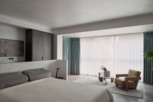 Minimalist bedroom with textured finishes, large window, and comfortable seating area.