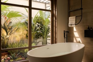 A minimalist bathroom featuring a freestanding bathtub with a serene indoor garden visible through the large window, providin