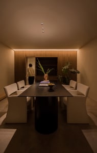 A modern interior space featuring a wooden table with white chairs, a vase of flowers, and a book.