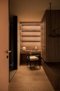 Modern closet with wooden walls and furniture, featuring a desk area with a chair, shelves, and a lit spherical lamp.