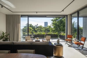 A modern living room features minimalist furniture, a large window, and a terrace with greenery.