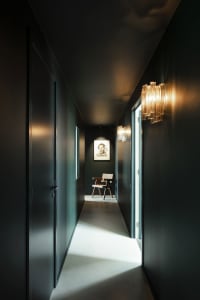 Modern, minimalist corridor with glass wall sconces and dark walls.