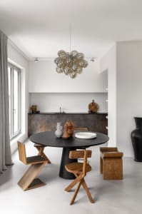 Modern minimalist kitchen with a round black table, wooden chairs, and a cluster of bubble chandelier