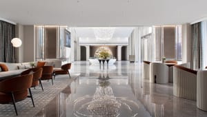 A modern hotel lobby with marble floors and white and brown furniture.