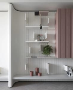 Modern white wooden bookshelf with green plant and decorative items.