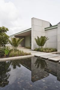 Modern residential exterior with concrete walls and a water feature.