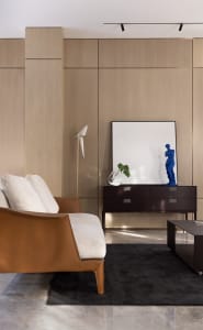 Modern living room with wood paneling, minimalist decor, and a blue sculpture on a cabinet.